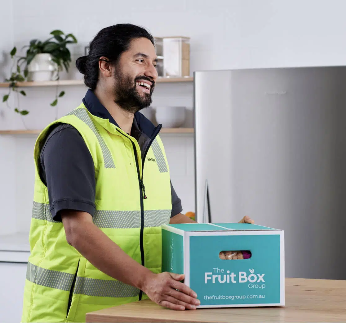 The Fruit Box Group team member holding a branded fruit box