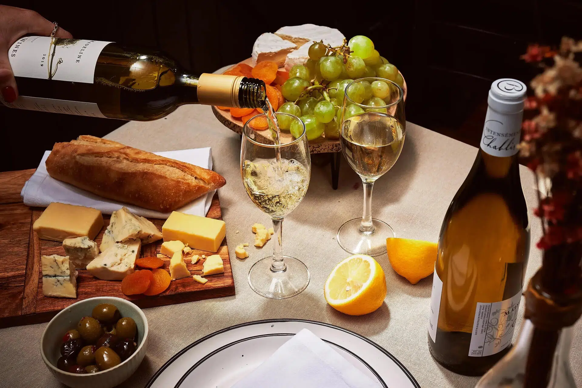Wine being poured into a glass beside a cheese board